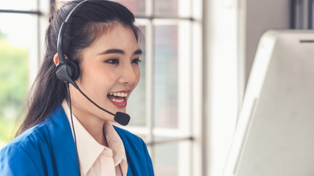 Businesswoman wearing headset working actively in office . Call center, telemarketing, customer support agent provide service on telephone video conference call.の写真素材