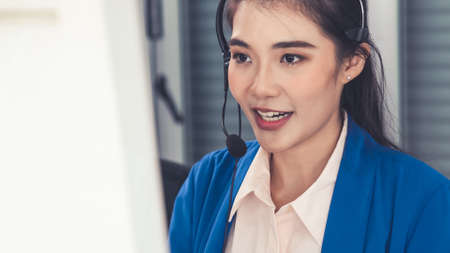 Businesswoman wearing headset working actively in office . Call center, telemarketing, customer support agent provide service on telephone video conference call.の写真素材