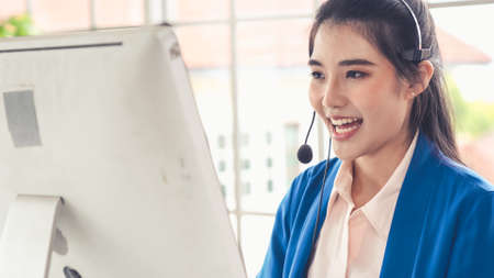 Businesswoman wearing headset working actively in office . Call center, telemarketing, customer support agent provide service on telephone video conference call.の写真素材