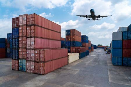 Cargo container for overseas shipping in shipyard with airplane in the sky . Logistics supply chain management and international goods export concept .の写真素材