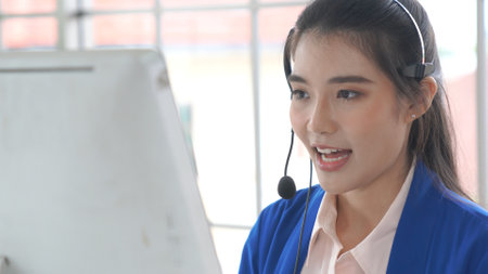 Businesswoman wearing headset working actively in office . Call center, telemarketing, customer support agent provide service on telephone video conference call.の写真素材