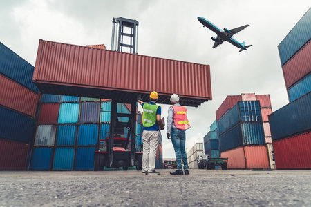 Industrial worker works with co-worker at overseas shipping container port . Logistics supply chain...