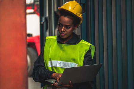 Young African American woman worker at overseas shipping container yard . Logistics supply chain...
