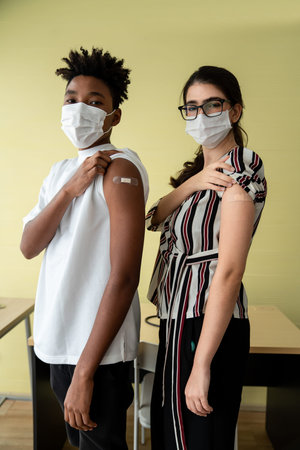 Diverse group of people showing COVID-19 vaccine bandage merrily in concept of coronavirus...