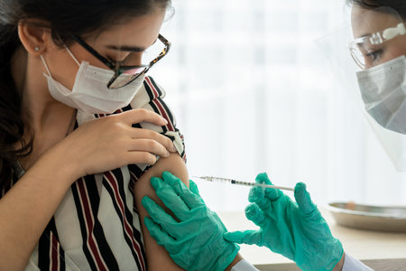 Young woman visits skillful doctor at hospital for vaccination . Covid 19 and coronavirus...