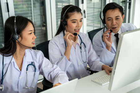 Doctor team wearing headset talking actively on video call in hospital clinic . Concept of telehealth and telemedicine service .の写真素材