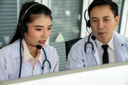 Doctor team wearing headset talking actively on video call in hospital clinic . Concept of telehealth and telemedicine service .の写真素材