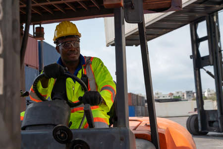 African american man driving forklift in shipyard . Logistics supply chain management and international goods export concept .の写真素材