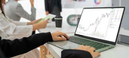 Businesswoman in analyze stock market data using laptop computer proficiently at the office while...