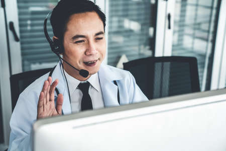 Doctor wearing headset talking actively on video call in a clinic or hospital . Concept of telehealth and telemedicine service .の写真素材