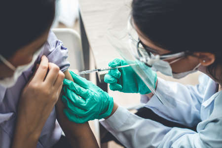 Young woman visits skillful doctor at hospital for vaccination . Covid 19 and coronavirus vaccination center service concept .の写真素材