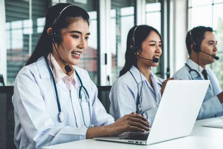 Doctor team wearing headset talking actively on video call in hospital clinic . Concept of telehealth and telemedicine service .の写真素材
