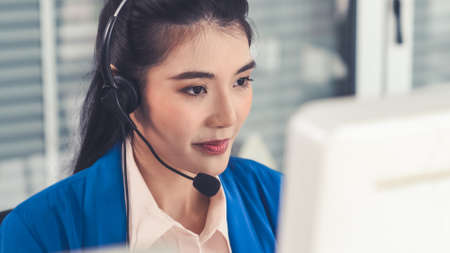 Businesswoman wearing headset working actively in office . Call center, telemarketing, customer support agent provide service on telephone video conference call.の写真素材