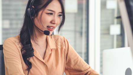 Businesswoman wearing headset working actively in office . Call center, telemarketing, customer support agent provide service on telephone video conference call.の写真素材