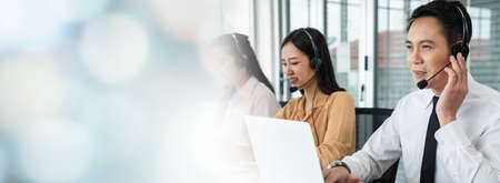 Business team wearing headset working actively in office . Call center, telemarketing, customer support agent provide service on telephone video conference call.の写真素材