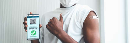African American teenager shows vaccine passport on mobile phone to validate travel permission by the digital documentの写真素材