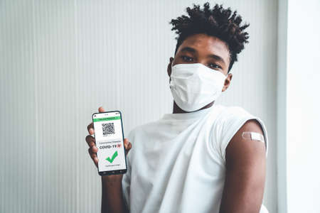 African American teenager shows vaccine passport on mobile phone to validate travel permission by the digital documentの写真素材