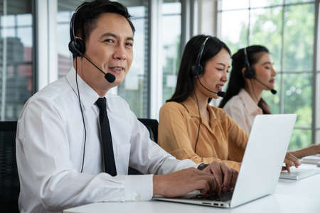 Business people wearing headset working actively in office . Call center, telemarketing, customer support agent provide service on telephone video conference call.の写真素材