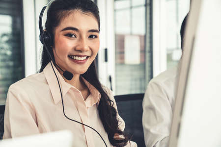 Businesswoman wearing headset working actively in office . Call center, telemarketing, customer support agent provide service on telephone video conference call.の写真素材