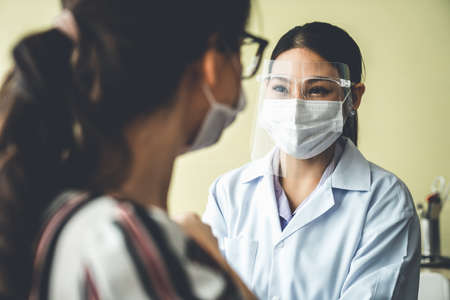 Young woman visits skillful doctor at hospital for vaccination . Covid 19 and coronavirus vaccination center service concept .の写真素材