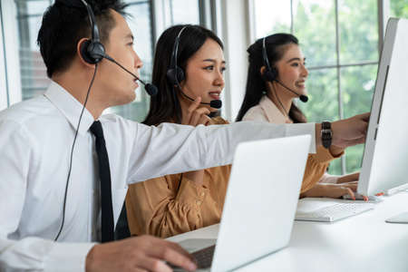 Business people wearing headset working actively in office . Call center, telemarketing, customer support agent provide service on telephone video conference call.の写真素材