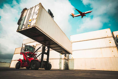 Cargo container for overseas shipping in shipyard with airplane in the sky . Logistics supply chain management and international goods export concept .の写真素材