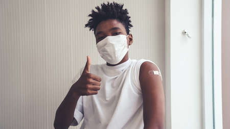 African American teenager showing COVID-19 vaccine bandage merrily in concept of coronavirus vaccination program to vaccinate citizen .の写真素材