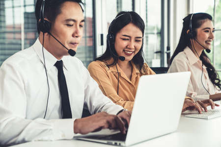 Business people wearing headset working actively in office . Call center, telemarketing, customer support agent provide service on telephone video conference call.の写真素材