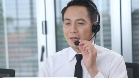 Businessman wearing headset working actively in office . Call center, telemarketing, customer support agent provide service on telephone video conference call.の写真素材
