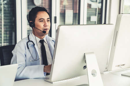 Doctor wearing headset talking actively on video call in a clinic or hospital . Concept of telehealth and telemedicine service .の写真素材