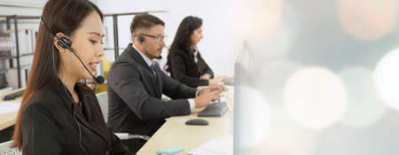 Business people wearing headset working in office to support remote customer or colleague. Call center, telemarketing, customer support agent provide service in broaden view .の写真素材