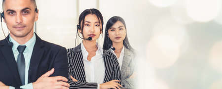 Business people wearing headset working in office to support remote customer or colleague. Call center, telemarketing, customer support agent provide service in broaden view .の写真素材