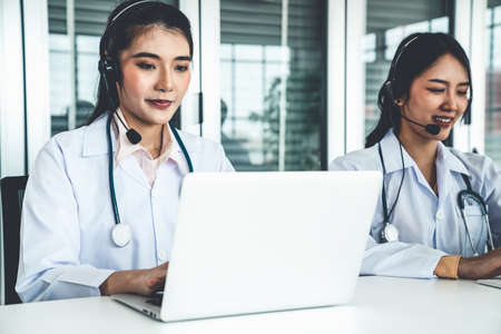 Doctor wearing headset talking actively on video call in hospital or clinic . Concept of telehealth and telemedicine service .の写真素材