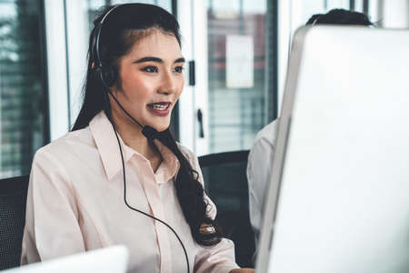 Businesswoman wearing headset working actively in office . Call center, telemarketing, customer support agent provide service on telephone video conference call.の写真素材