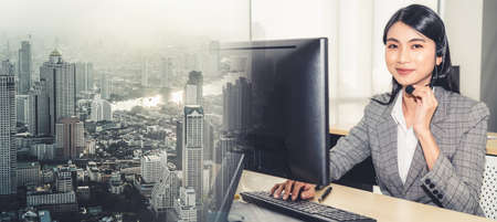 Business people wearing headset working in office to support remote customer or colleague. Call center, telemarketing, customer support agent provide service in broaden view .の写真素材