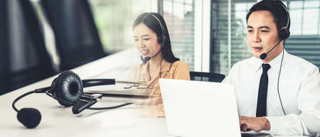 Business team wearing headset working actively in office . Call center, telemarketing, customer support agent provide service on telephone video conference call.の写真素材
