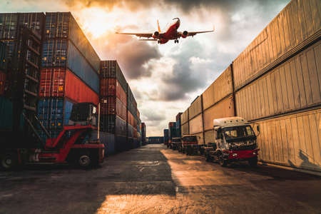 Cargo container for overseas shipping in shipyard with airplane in the sky . Logistics supply chain management and international goods export concept .の写真素材