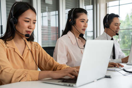 Business people wearing headset working actively in office . Call center, telemarketing, customer support agent provide service on telephone video conference call.の写真素材