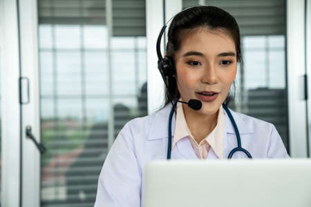 Doctor wearing headset talking actively on video call in hospital or clinic . Concept of telehealth and telemedicine service .の写真素材