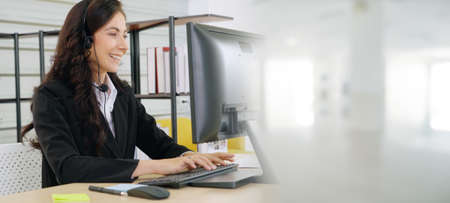 Business people wearing headset working in office to support remote customer or colleague. Call center, telemarketing, customer support agent provide service in broaden view .の写真素材