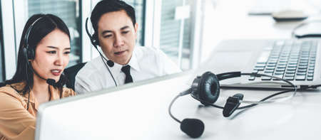 Business team wearing headset working actively in office . Call center, telemarketing, customer support agent provide service on telephone video conference call.の写真素材