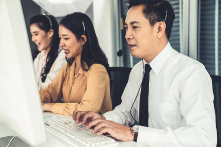 Business people wearing headset working actively in office . Call center, telemarketing, customer support agent provide service on telephone video conference call.の写真素材