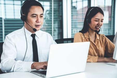 Business people wearing headset working actively in office . Call center, telemarketing, customer support agent provide service on telephone video conference call.の写真素材