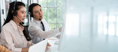 Business team wearing headset working actively in office . Call center, telemarketing, customer support agent provide service on telephone video conference call.の写真素材