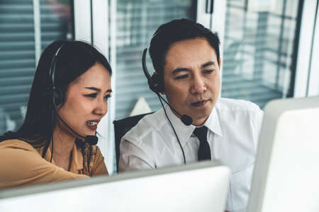 Business people wearing headset working actively in office . Call center, telemarketing, customer support agent provide service on telephone video conference call.の写真素材