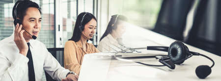 Business team wearing headset working actively in office . Call center, telemarketing, customer support agent provide service on telephone video conference call.の写真素材