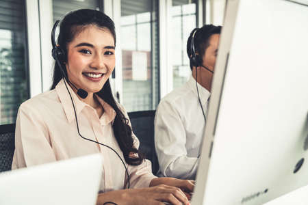 Business people wearing headset working actively in office . Call center, telemarketing, customer support agent provide service on telephone video conference call.の写真素材