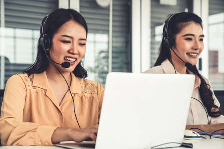 Business people wearing headset working actively in office . Call center, telemarketing, customer support agent provide service on telephone video conference call.の写真素材