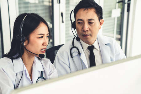 Doctor team wearing headset talking actively on video call in hospital clinic . Concept of telehealth and telemedicine service .の写真素材