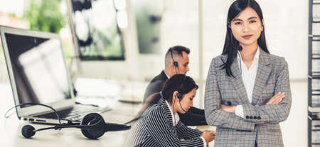 Business people wearing headset working in office to support remote customer or colleague. Call center, telemarketing, customer support agent provide service in broaden view .の写真素材